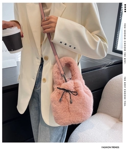 Detail of pink faux fur bucket bag featuring drawstring bow and metallic pendant detail