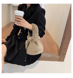 Detail of beige faux fur bucket bag with drawstring closure held by a model