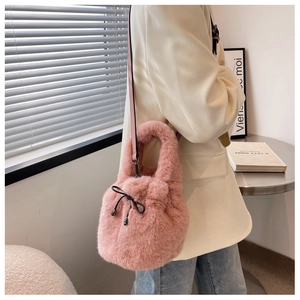 Close-up of pink plush bucket bag with drawstring closure and metal pendant detail