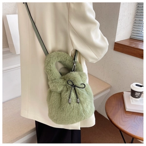 Detail of green plush bucket bag with black bow decoration and drawstring closure