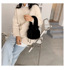 Detail of black faux fur bucket bag with drawstring closure and matching plush handle