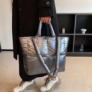 Detail of silver metallic quilted tote bag with wide shoulder strap and puffer texture