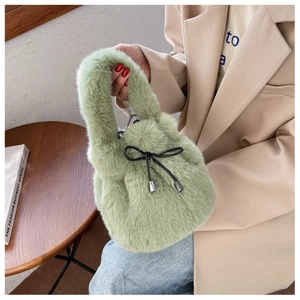 Close-up of light green faux fur bucket bag with black drawstring bow and metallic tips