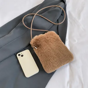 Detail presentation of compact brown plush phone bag showing size compared to a smartphone