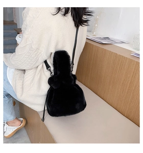 Detailed view of plush faux fur bucket bag texture with leather strap on a model