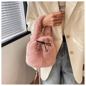 Detail of pink plush bucket bag with drawstring closure and metal charms on model