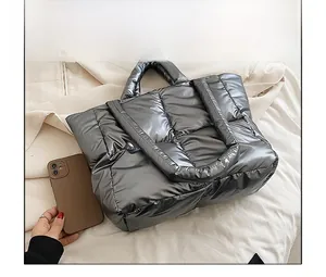 Detailed comparison of silver quilted down tote bag size with a smartphone display