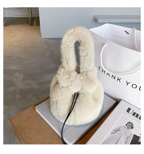 Detail of plush bucket bag in cream faux fur with drawstring on a stylish magazine