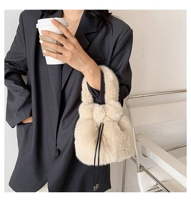 Close-up of a cream plush bucket bag with black drawstring in a lifestyle fashion setting