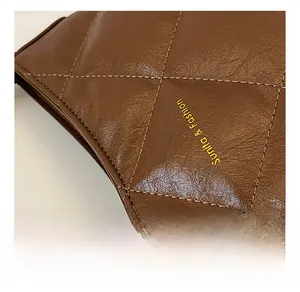 Detail of dark brown quilted leather handbag with gold Sunita & Fashion logo branding