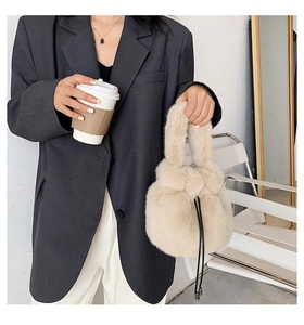Detail showing the drawstrings and soft faux fur texture of the beige bucket bag