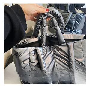 Close-up of padded top handle and metallic quilted fabric on a silver puffer tote bag