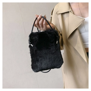 Detail of black faux fur plush handbag with soft texture and drawstring knot design