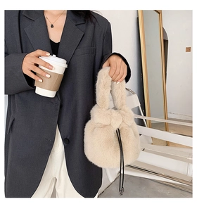 Chic beige faux fur drawstring bucket bag shown in a stylish urban lifestyle setting