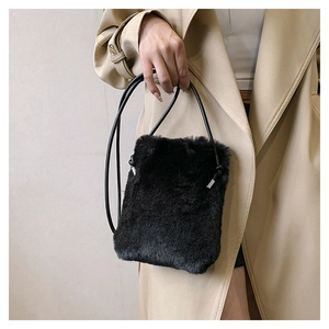 Detail of a black plush crossbody bag worn with a khaki trench coat for winter
