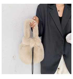 Detail of beige faux fur bucket bag with black drawstring closure and soft texture