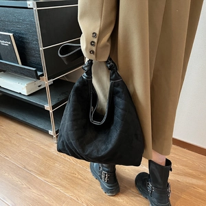 Large black quilted hobo bag with knotted handle shown on model in trench coat