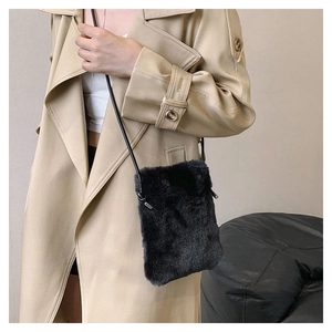 Detail of black faux fur mini crossbody bag worn with a classic beige trench coat