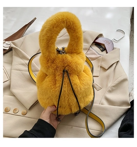 Close-up of bright yellow faux fur bucket bag with drawstring and leather strap