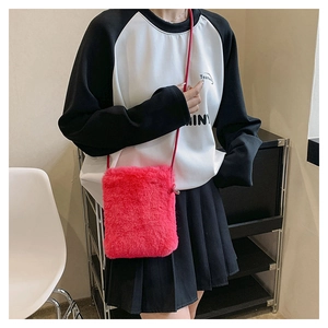 Close-up of rose red plush crossbody phone bag showing soft faux fur texture on model