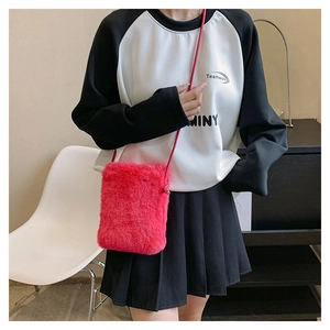 Close-up of fluffy hot pink plush crossbody bag with red strap on a model outfit