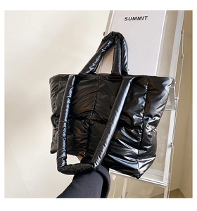 Close-up of shiny black quilted puffer tote bag with thick padded handles for winter style