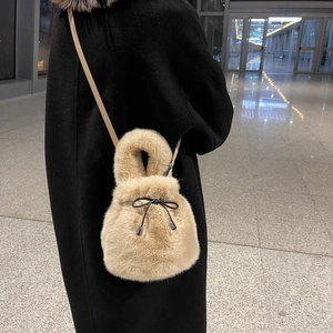 Chic khaki faux fur bucket bag with drawstring and shoulder strap worn by a model