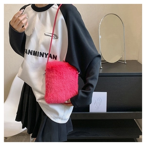 Detail shot of a bright pink plush crossbody phone bag with slim leather strap