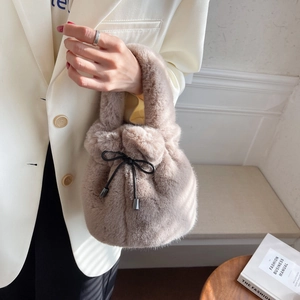Chic plush drawstring bucket bag in light brown with a decorative black bow detail