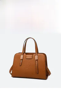 Detail of brown crocodile pattern embossed handbag with gold metal hardware and logo