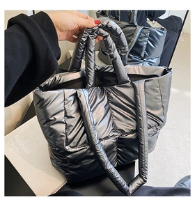 Close-up of metallic silver quilted tote bag with padded handles and puffer down texture