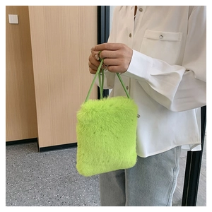 Detail of neon green faux fur crossbody bag with fluffy texture and thin strap