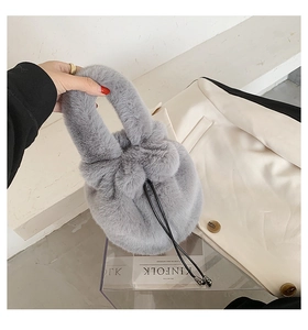 Detail of grey plush drawstring bucket bag held by hand with elegant soft texture