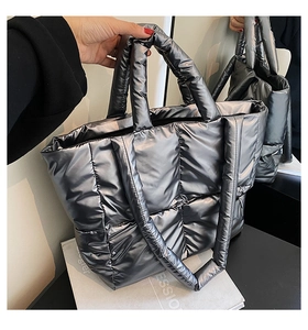 Detail of silver quilted puffer tote bag featuring metallic finish and wide shoulder strap