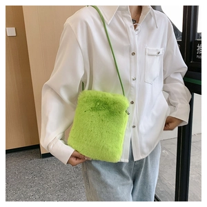 Detail of neon green faux fur crossbody bag texture and slim strap on female model