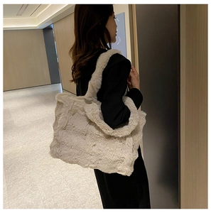 Vue détaillée d'un sac cabas en fausse fourrure blanc crème porté à l'épaule par un mannequin