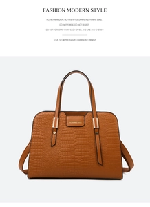 Detail of tan crocodile pattern handbag with gold hardware and stylish branding