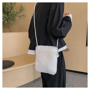 Detail of soft white faux fur crossbody bag with thin strap and plush texture