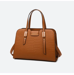 Close-up of brown crocodile texture tote bag with metal buckle and shoulder strap