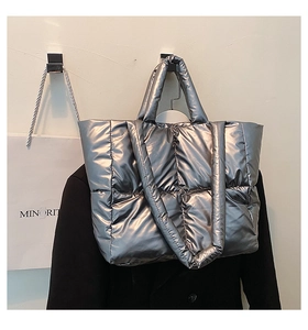 Detail of metallic silver quilted tote bag with padded texture and wide shoulder straps