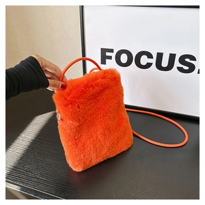 Detail of orange plush crossbody bag showing soft faux fur texture and metal zipper