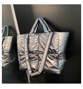 Close-up of quilted silver metallic tote bag featuring padded down texture and wide strap