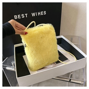 Detail of yellow plush faux fur crossbody bag with sleek strap in a gift box
