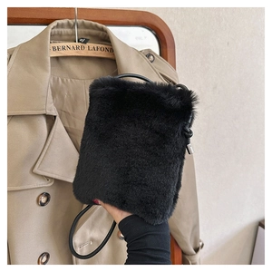 Detail of black faux fur plush crossbody bag with leather strap and silver metal buckle