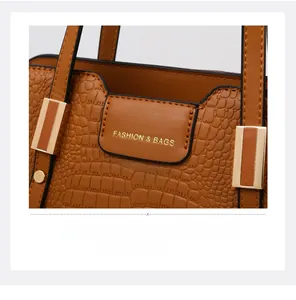 Detail of brown crocodile pattern handbag with gold fashion lettering and metal buckle