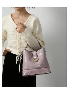 Detail view of pink crocodile embossed bucket bag with gold D-ring and snakeskin trim