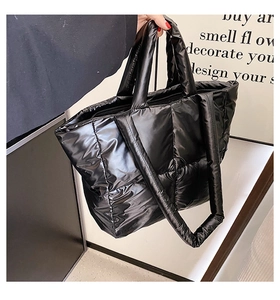 Detail of black quilted down tote bag in high-gloss nylon with top handles and strap