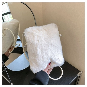 Mirror reflection showing side view of soft white plush crossbody bag with metal accents