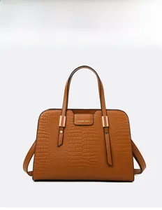 Detail of brown crocodile embossed texture on luxury tote bag with gold metal hardware