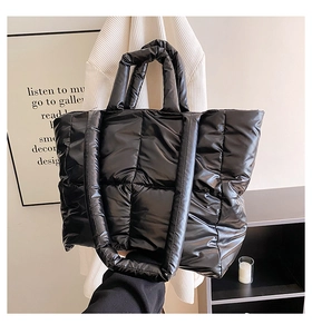 Close-up of black puffer tote bag with diamond quilting and dual strap design details